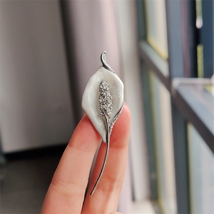 Macro view of Calla Lily brooch with white enamel petals and sparkling rhinestones