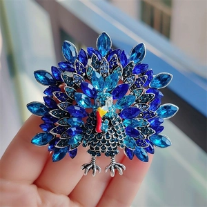 Handheld peacock brooch featuring blue crystals and silver-tone alloy base