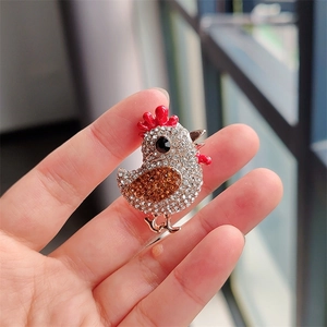 Détails d'une broche poussin étincelante en strass avec des accents d'émail rouge