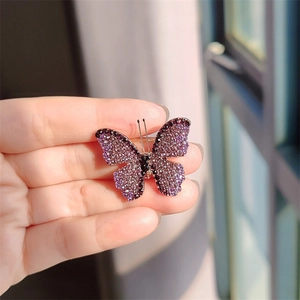 Detail view of butterfly brooch featuring purple gradient rhinestones on a gold base