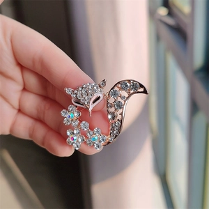 Detailed close-up of a rose gold fox brooch with white rhinestones and flower crystals