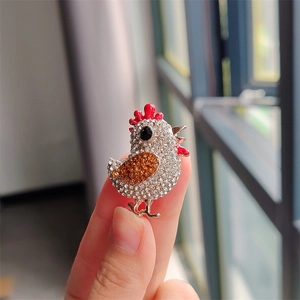 Broche poussin scintillante avec cristaux blancs et ambrés et émail rouge sur alliage