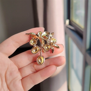 Detail view showing the secure pin clasp and gold alloy finish on the lychee brooch back