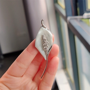 Detailed view of Calla Lily brooch with white pearlescent petals and crystal inlay