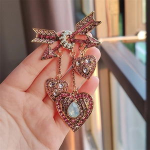 Détail de la broche flèche de Cupidon avec zircons roses et pendentifs à pompons