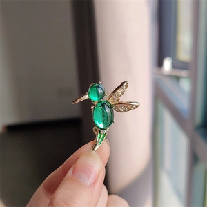 Elegant emerald hummingbird brooch with gold wings and sparkling crystal accents