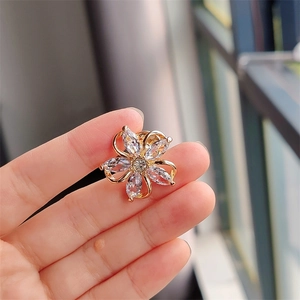 Detailed close-up of a golden hollow five-petal flower brooch with marquise zircon stones