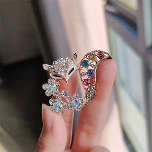 Close-up of golden fox brooch with white rhinestones and colorful gemstones detail