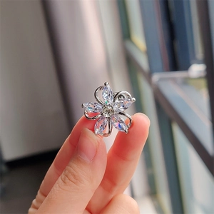 Exquisite hollow five-petal flower brooch with zircons held by hand in natural light