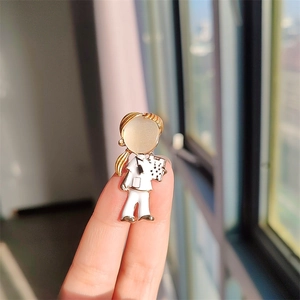 Broche de médecin avec visage en opale et blouse blanche tenue entre les doigts