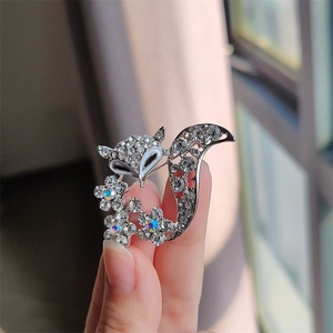Detailed view of silver fox brooch with white crystals and iridescent floral accents