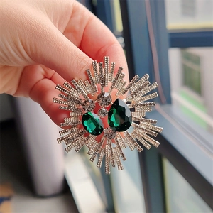 Detail of vintage silver brooch with emerald green teardrop crystals held in hand