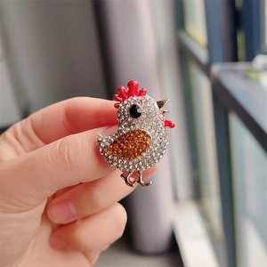 Détail macro d'une broche en forme de poulet sertie de strass brillants et dorés