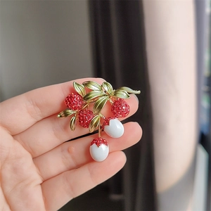 Detail of sweet lychee brooch with red crystals, green leaves and pearl drops