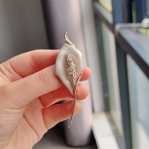 Close-up of elegant cream calla lily brooch with rose gold finish and sparkling crystals