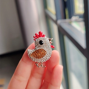 Détail d'une broche en forme de coq en cristal étincelant avec accents ambre et émail