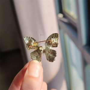 Detailed back view of golden butterfly brooch showing metal texture and pin fastener