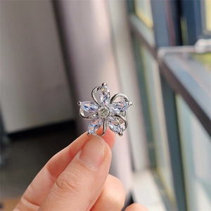 Close-up of five-petal flower brooch with marquise-cut zircon held by hand near a window
