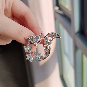 Macro detail of fox brooch with rose gold plating and white rhinestones on hand