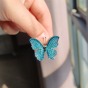 Exquisite blue gradient butterfly brooch with shimmering rhinestones held by hand