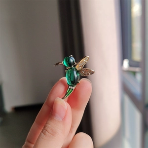 Elegant hummingbird brooch with green cat-eye stones and crystal wings in gold finish