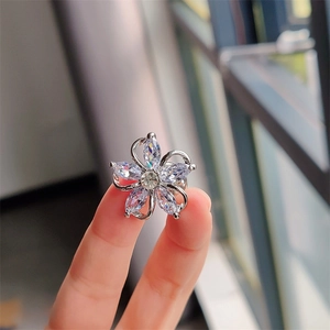Macro shot of a five-petal flower brooch with marquise-cut zircon held by fingers