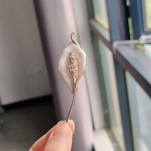 Close-up of elegant Calla Lily brooch with white enamel petals and sparkling rhinestones