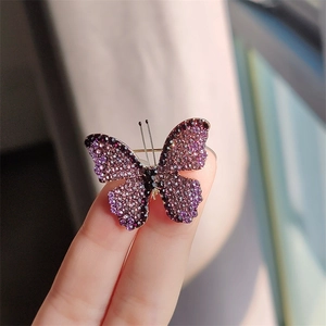 Detailed butterfly brooch featuring purple and black crystals shown on fingertips