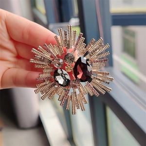 Detailed close-up of a vintage sunburst brooch featuring a large teardrop purple gemstone
