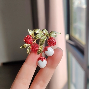 Elegant lychee fruit brooch with red rhinestones and white enamel on a gold branch