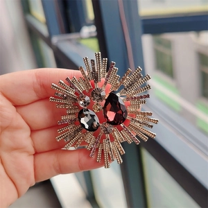 Detail of vintage starburst brooch with burgundy crystals and gold-tone metal work