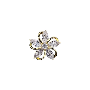 Golden five-petal flower brooch with marquise-cut cubic zirconia in a white background