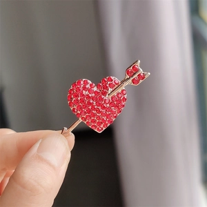 Gros plan d'une broche cœur avec strass rouges et finition dorée élégante