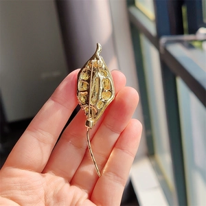 Detailed back view of a golden leaf brooch showing the pin clasp and matte texture
