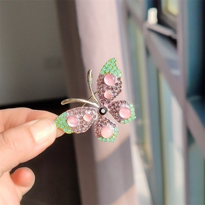 Gedetailleerde weergave van vlinderbroche met roze opaal en paarse strass