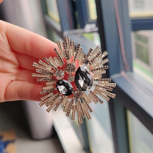Detailed close-up of a vintage sunburst crystal brooch with gold base and black gems