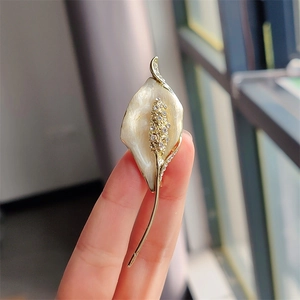 Close-up of elegant Calla Lily brooch with cream enamel and sparkling white crystals