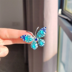Macro detail van vlinderbroche met blauwe kristallen en kattenoogstenen in de hand