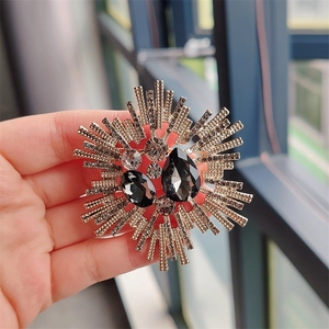 Macro shot of a vintage golden sunburst brooch with dark grey crystals held in hand