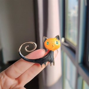 Detailansicht der orange-schwarzen Katzenbrosche aus Emaille mit grünen Edelsteinaugen