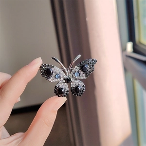 Gedetailleerde weergave van zilveren vlinderbroche met zwarte kralen en strass