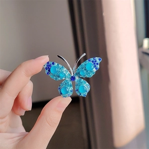 Gedetailleerde close-up van vlinderspeld met blauwe strass steentjes en opaal