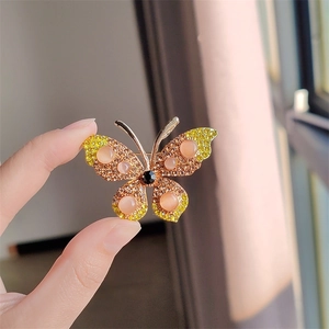 Glinsterende vlinderbroche met strass en oranje kattenoogstenen in vintage gouden stijl