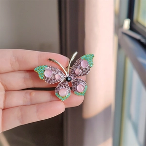 Detail van de vlinderbroche met paarse strassteentjes en roze kattenoogsteentjes
