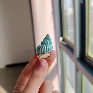 Dettaglio ravvicinato di una spilla a conchiglia blu con opale bianco e cristalli