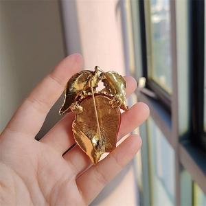 Macro detail of strawberry brooch back showing the secure gold metal pin clasp