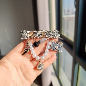 Détail d'une broche en tweed avec chaîne dorée et breloques perles Tour Eiffel