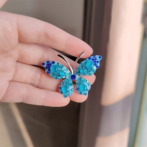 Zilveren vlinderbroche met blauwe gradiënt steentjes en elegante kattenoog-edelstenen