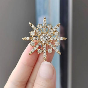 Elegant gold snowflake brooch with sparkling crystals and a radiant starburst pattern