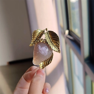 Detailed close-up of a pink resin strawberry brooch with golden textured leaves